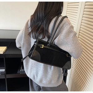 Detail of black leather and suede shoulder bag with gold metal buckle and dual handles