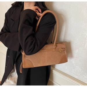 Detail of caramel leather patchwork bag with sleek metal buckle and stylish tassel