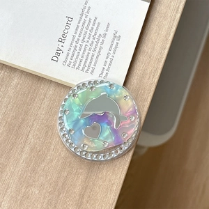 Macro view of holographic dolphin phone grip with rhinestones on a wooden surface