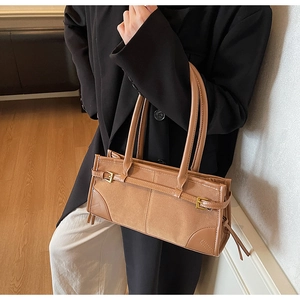 Detail of camel tote bag with suede texture, gold buckle, and stylish tassels