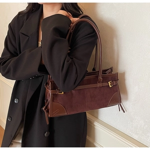 Close-up of vintage brown rectangular shoulder bag with suede textures and gold buckles