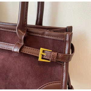 Detail of caramel suede and leather texture contrast with gold buckle on tote bag