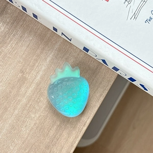Colorful strawberry phone grip on a minimalist wooden table with a magazine