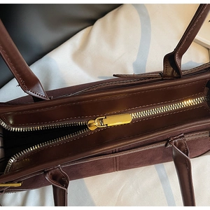 Detail of gold zipper closure and textured leather patchwork on the wine red tote bag