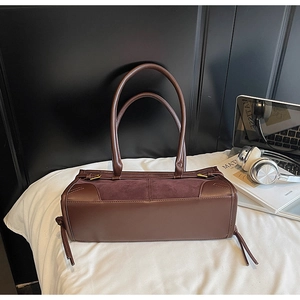 Detail of dark brown tote bag showing smooth leather and suede texture with tassel accents