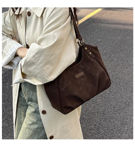 Detail of vintage dark brown suede shoulder bag with metal ring buckle and crescent design