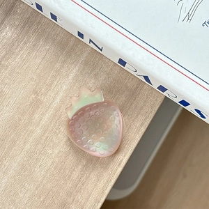 Macro view of a colorful gradient strawberry phone grip with pearl finish on a wooden desk