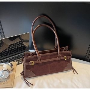 Detail of dark brown tote bag featuring suede texture and gold buckle decoration