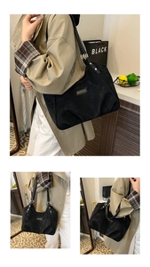 Detail view of black matte tote bag with metallic logo plate and leather shoulder strap