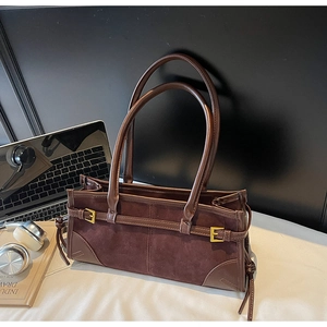 Detail of dark brown suede tote bag with long straps, metal buckle and side tassels