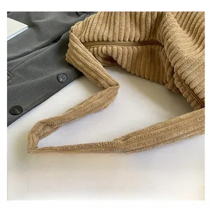 Detail of khaki corduroy shoulder bag showing wide strap and thick ribbed texture