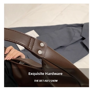 Detail of silver rivets and smooth dark brown leather stitching on a tote bag handle