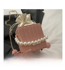 Close-up of pink woven bucket bag with pearl handle and cream drawstring closure