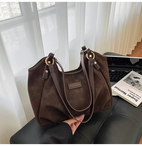 Detail of dark brown faux suede tote bag with leather straps and vintage gold hardware