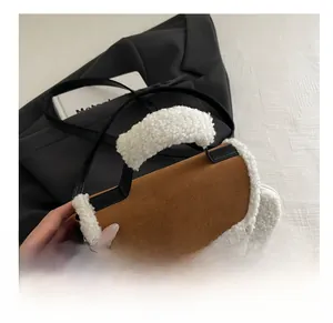 Dettaglio della borsa in pelle scamosciata marrone con bordi in lana bianca e manici neri