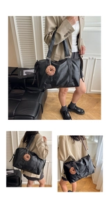 Detail of large black leather tote bag featuring a cute brown donut plush charm attachment