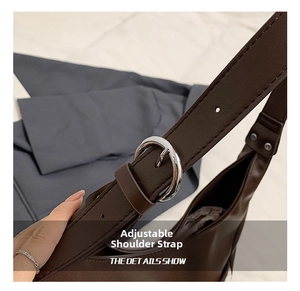 Detail of adjustable dark brown leather strap with silver buckle on the tote bag
