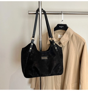 Detail of black matte suede shoulder bag with gold metal rings and rivet accents