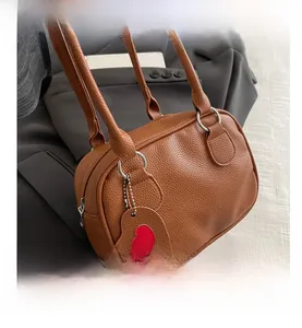 Brown litchi grain leather bowling bag with silver rings and a red heart charm