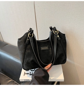 Detail of black suede tote bag featuring gold ring hardware and sleek leather straps