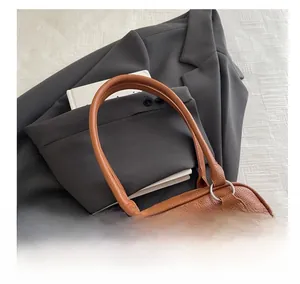 Brown litchi leather handbag detail with silver hardware on a professional blazer