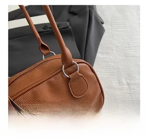 Detail of brown litchi pattern PU leather handbag with silver metal ring connectors