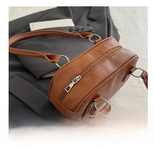 Detailed close-up of brown litchi grain shoulder bag with smooth silver zipper and hardware