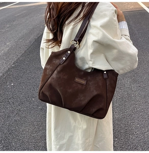 Detailed view of the dark brown suede tote bag with pleated base and golden rings
