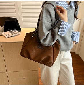 Detailed close-up of brown suede tote bag featuring premium metal hardware and leather strap
