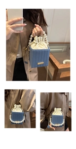Détail du sac seau bleu tressé avec poignée en perles et bandoulière en chaîne dorée