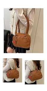 Detail of brown litchi pattern leather handbag with heart pendant and silver hardware