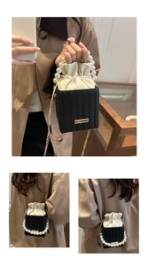Détails d'un mini sac seau tressé noir avec anse en perles et chaîne dorée