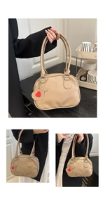 Detail of beige litchi grain handbag with red heart charm and silver metal rings
