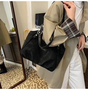 Detail of a large black matte leather tote bag with elegant metallic ring strap connector