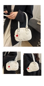 Close-up of white pebble leather handbag with a red heart charm and silver hardware