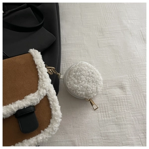 Close-up of white fleece coin purse charm with gold zipper on brown suede tote bag
