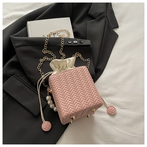 Detail view of pink woven box bag with drawstring satin lining and golden chain strap