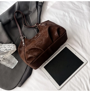 Detail of dark brown suede hobo bag shown with an iPad to highlight its large capacity