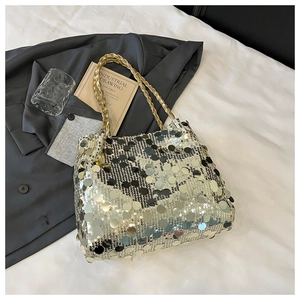 Detail der silbernen Pailletten-Tasche mit goldenem Trageriemen auf weißem Stoffhintergrund