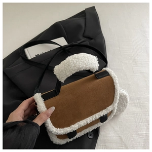Detailed view of the brown suede saddle bag with white plush trim and black leather straps