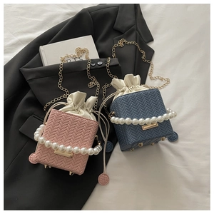 Detail of woven texture bucket bag with large pearl handle and drawstring closure