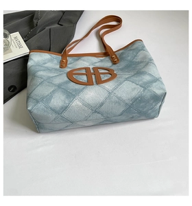 Detail of denim print tote bag with rhombus quilting and brown leather letter accent