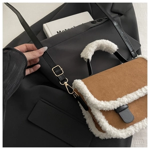 Detail of brown suede crossbody bag with white faux fur trim on grey blazer