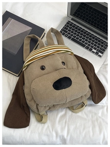Detail view of khaki corduroy puppy backpack with adjustable straps on a desk