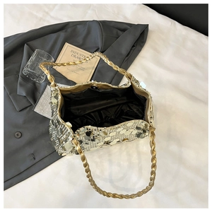 Detailansicht der goldenen Metallpailletten auf einer schicken Tasche mit Kordelgriff