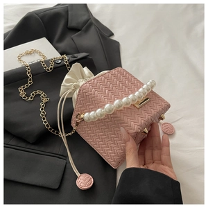 Detail of pink woven box bag with large pearl handle and gold chain strap