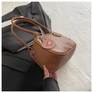 Détail du sac à main marron à motif litchi avec pendentif en forme de cœur créatif