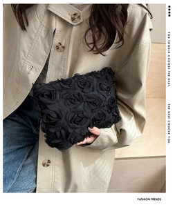 Detailed close-up of 3D fabric rose petals on this elegant black evening clutch handbag