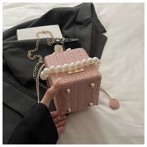 Detail of pink woven bucket bag featuring large pearl handle and gold chain strap
