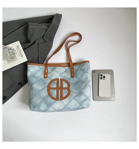 Detailed top view of large denim tote bag with quilted pattern and brown leather B logo